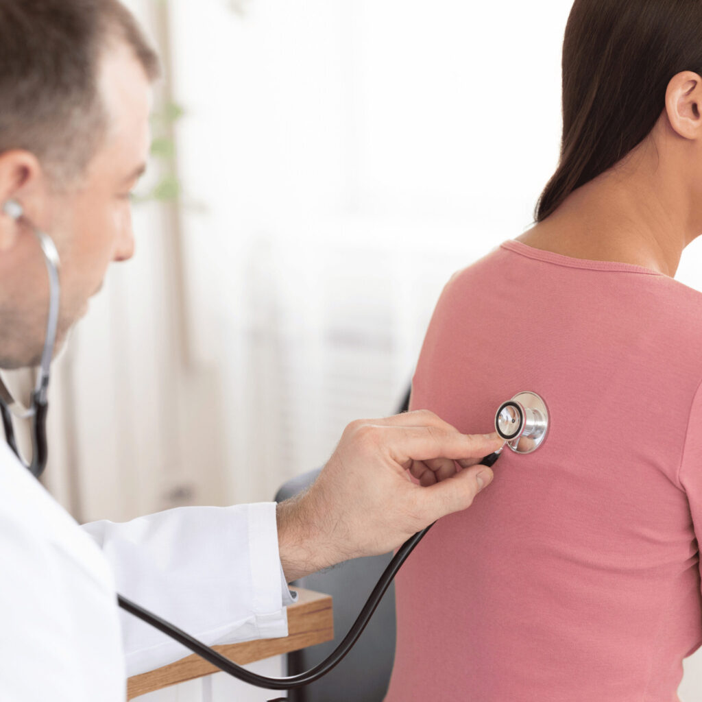 Experienced doctor checking breath of female patient