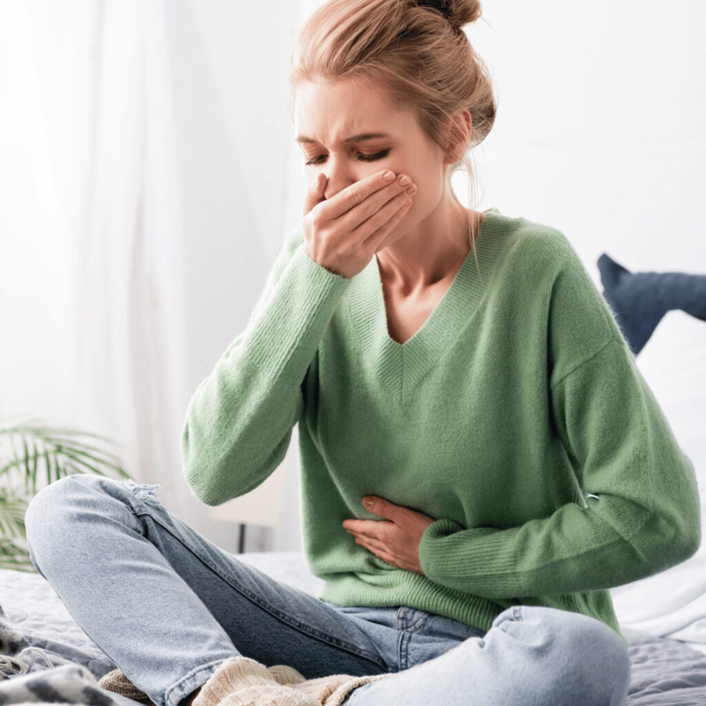 woman having nausea and sitting on bed