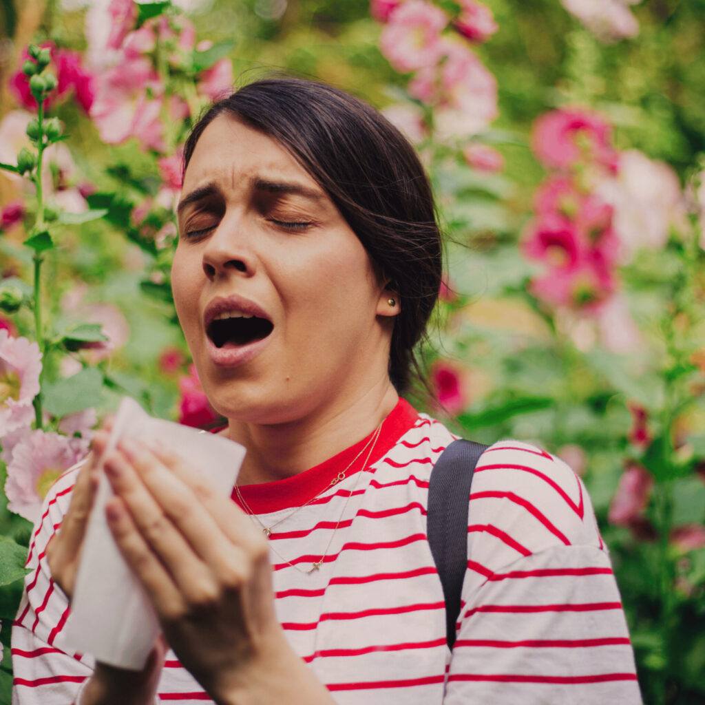 woman sneezing, allergy to flowers or pollen